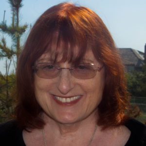 A woman with glasses and red hair sitting on a couch.